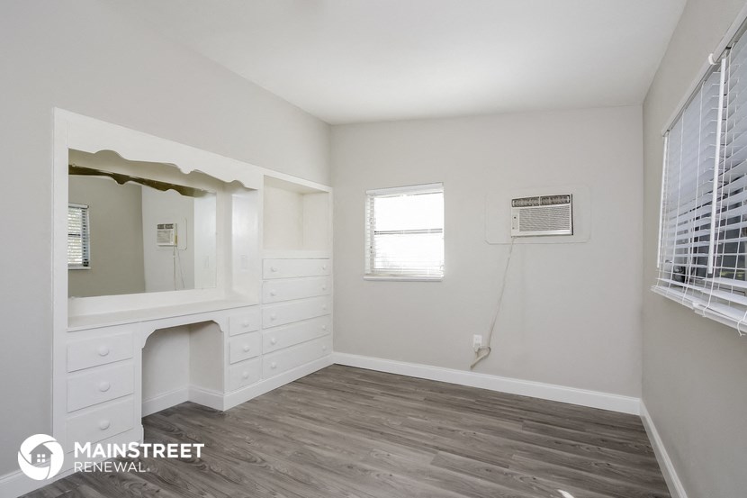 a room with white cabinets and a mirror and a window