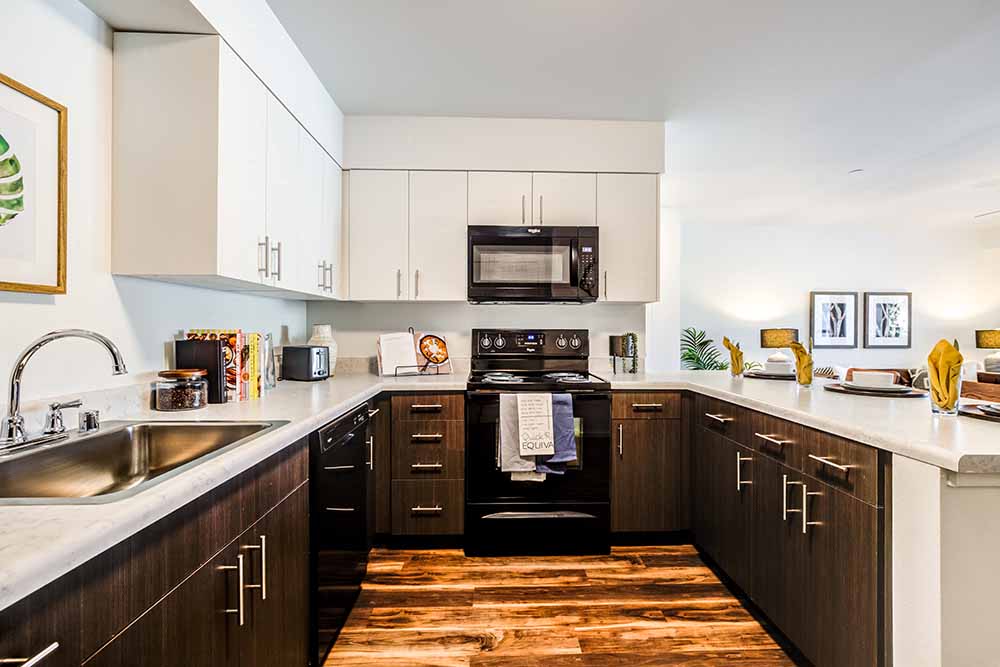 A modern kitchen with dark wood cabinets and a white countertop.