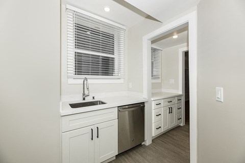 A kitchen with white cabinets and a stainless steel dishwasher.