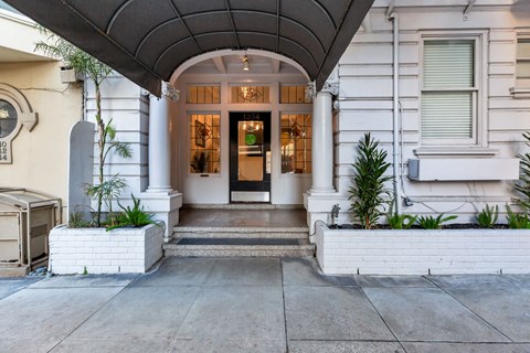 A white building with a black door and a green sign above it.