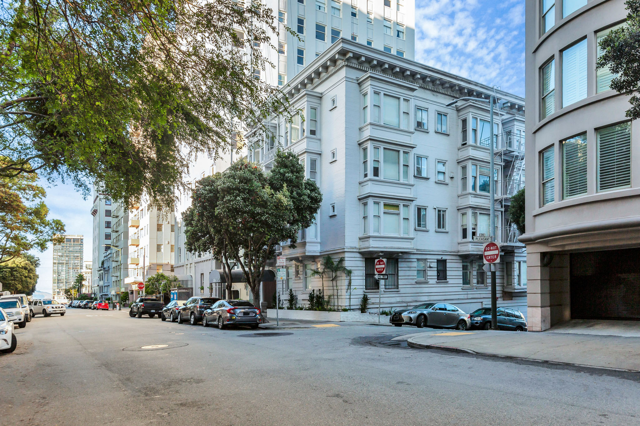 A street view of a residential area with cars parked on the side of the road.