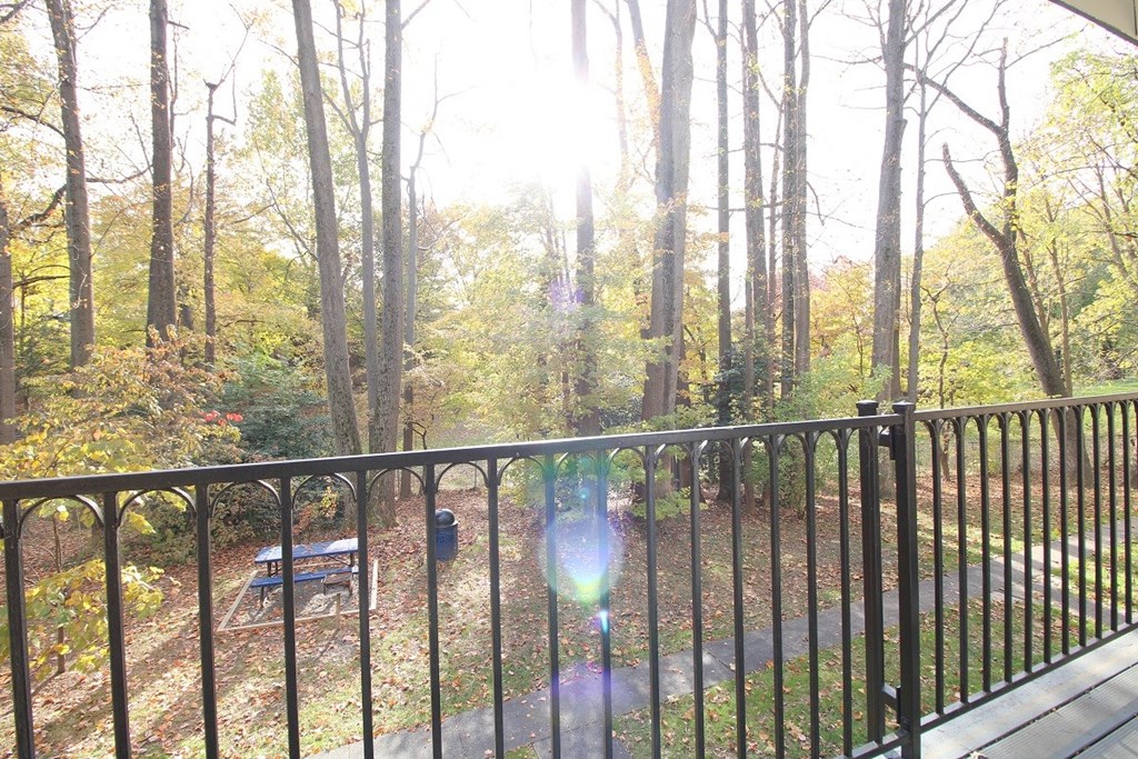 a balcony with a view of a wooded area and a fence