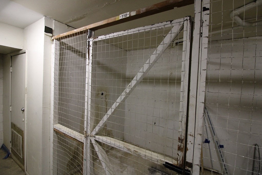 a large metal cage in a room with white tiled walls