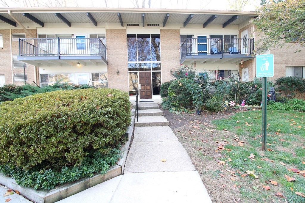 the front of an apartment building with a sidewalk and walkway