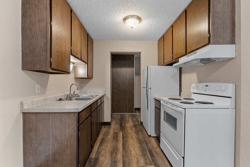 A kitchen with white appliances and wooden cabinets.