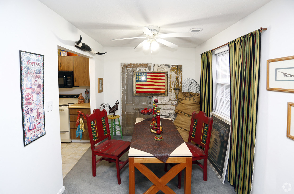 a dining area with a table and chairs and a kitchen in the background