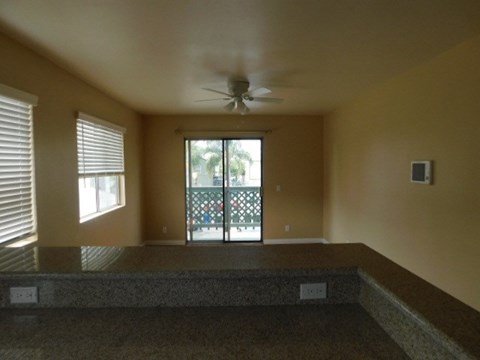 A room with a ceiling fan and sliding glass doors.
