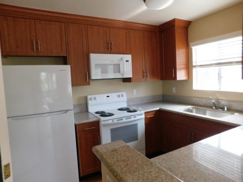 A kitchen with brown cabinets and a white fridge.