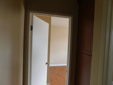 A white door is open to a room with wooden flooring.