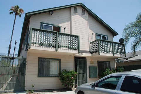 A two-story house with a balcony and a car parked in front.