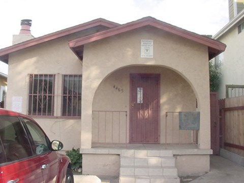 A small house with a red door and a sign on the wall.