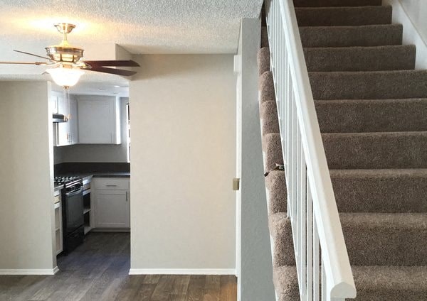 an empty staircase in a home with a kitchen and a ceiling fan