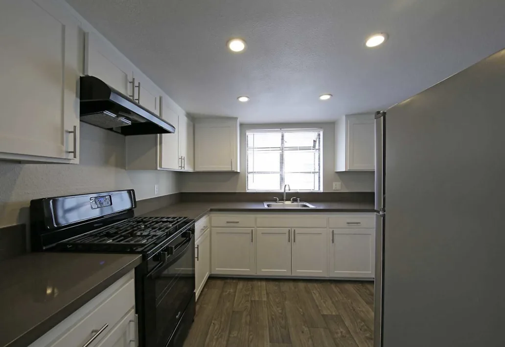 an empty kitchen with white cabinets and black appliances