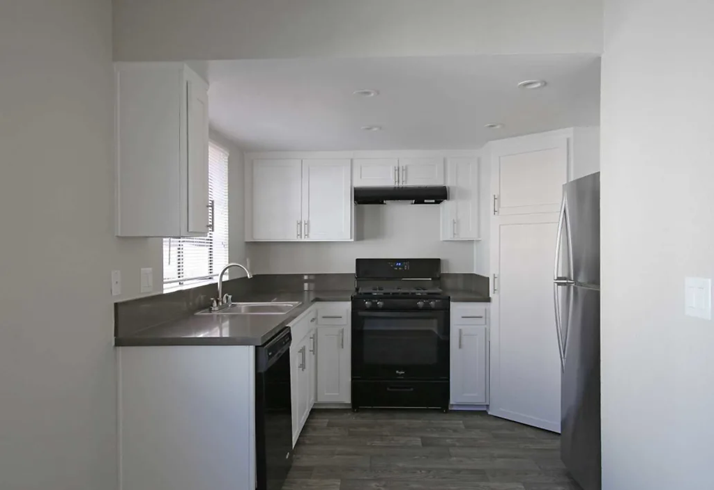 an empty kitchen with black appliances and white cabinets