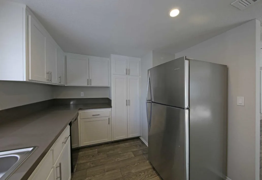 a kitchen with white cabinets and a stainless steel refrigerator