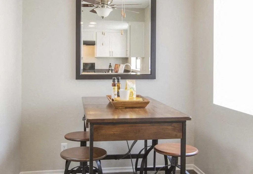 a small bar with four stools under a mirror in a room