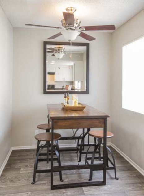 a kitchen with a table and stools and a ceiling fan
