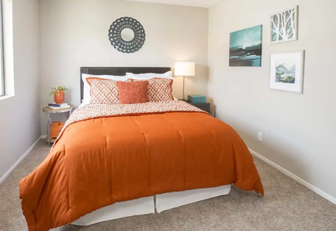 a bedroom with an orange comforter and orange pillows