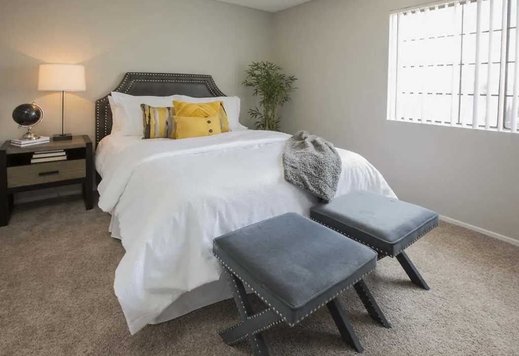 a bedroom with a bed and two stools