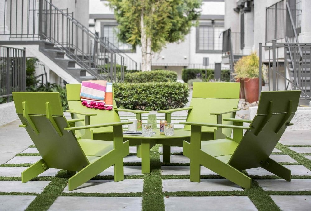 a patio with green chairs and tables on a lawn