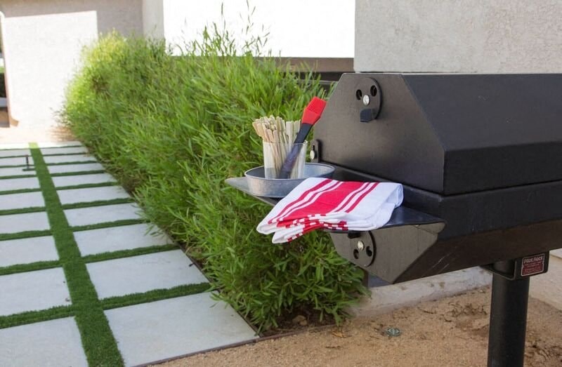 a grill with a pair of utensils in the grass