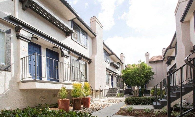 a row of houses with blue doors and a sidewalk