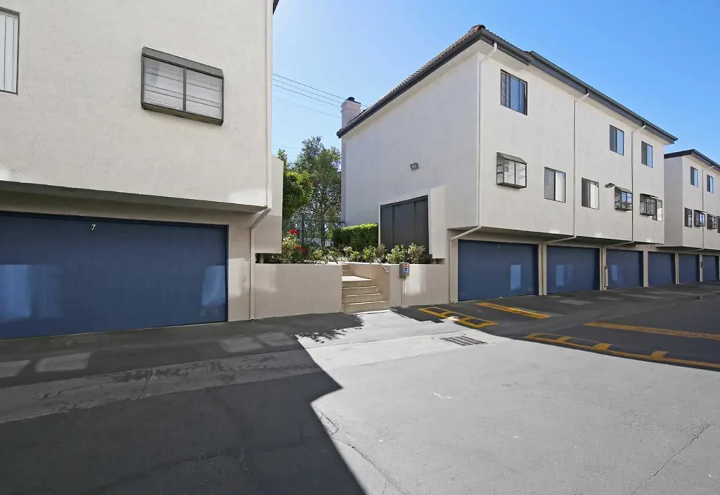 a parking lot in front of two buildings with blue garage doors