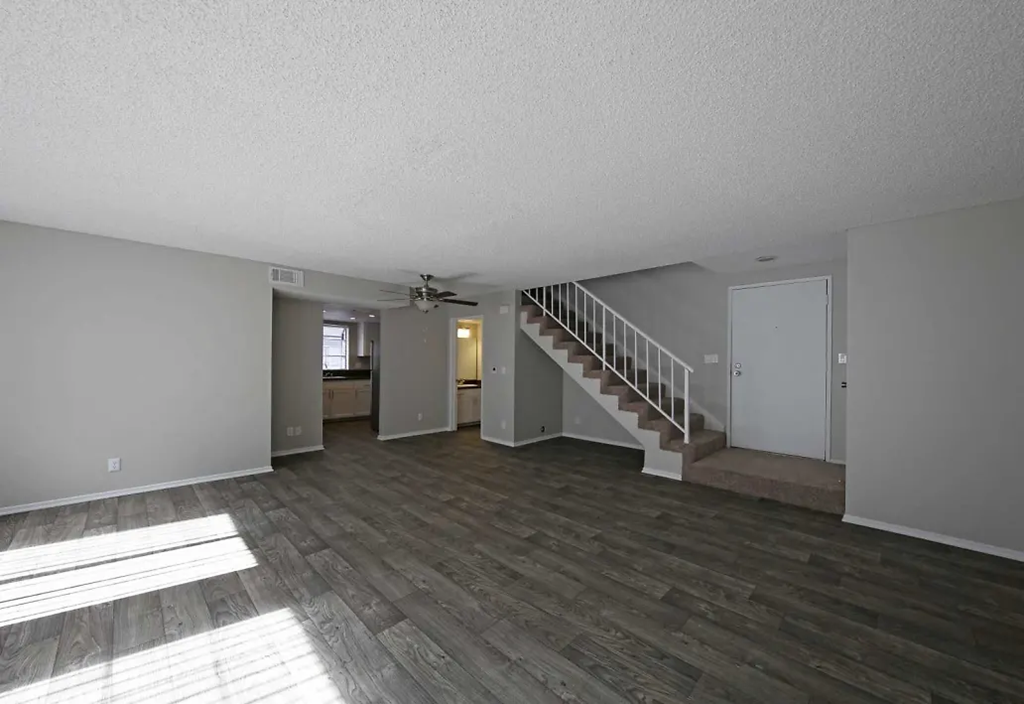 a living room with a staircase and a hard wood floor