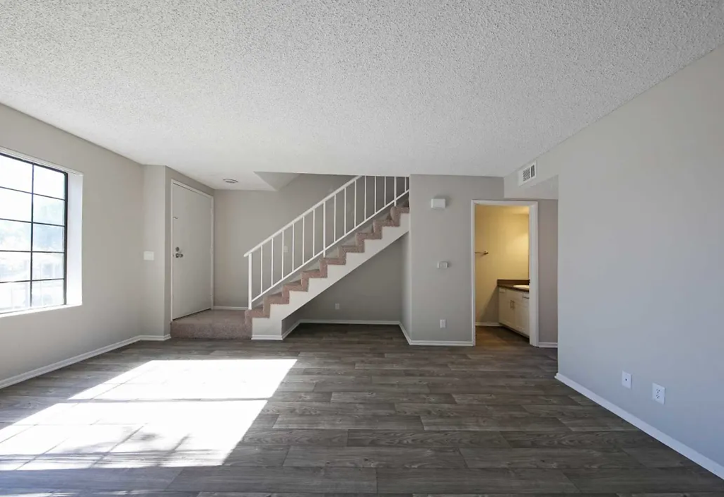 the living room and staircase of a house with a wooden floor