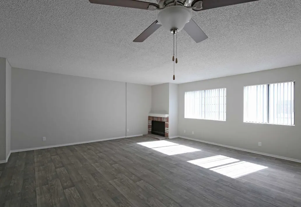 an empty living room with a ceiling fan