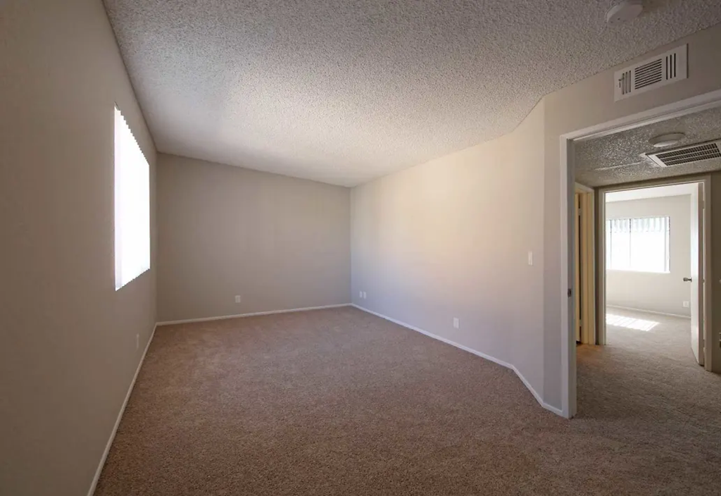 an empty living room with a door to a bedroom