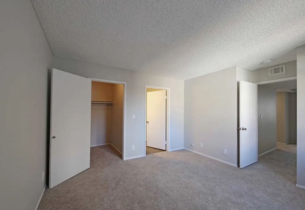 an empty living room with white walls and a door to a closet