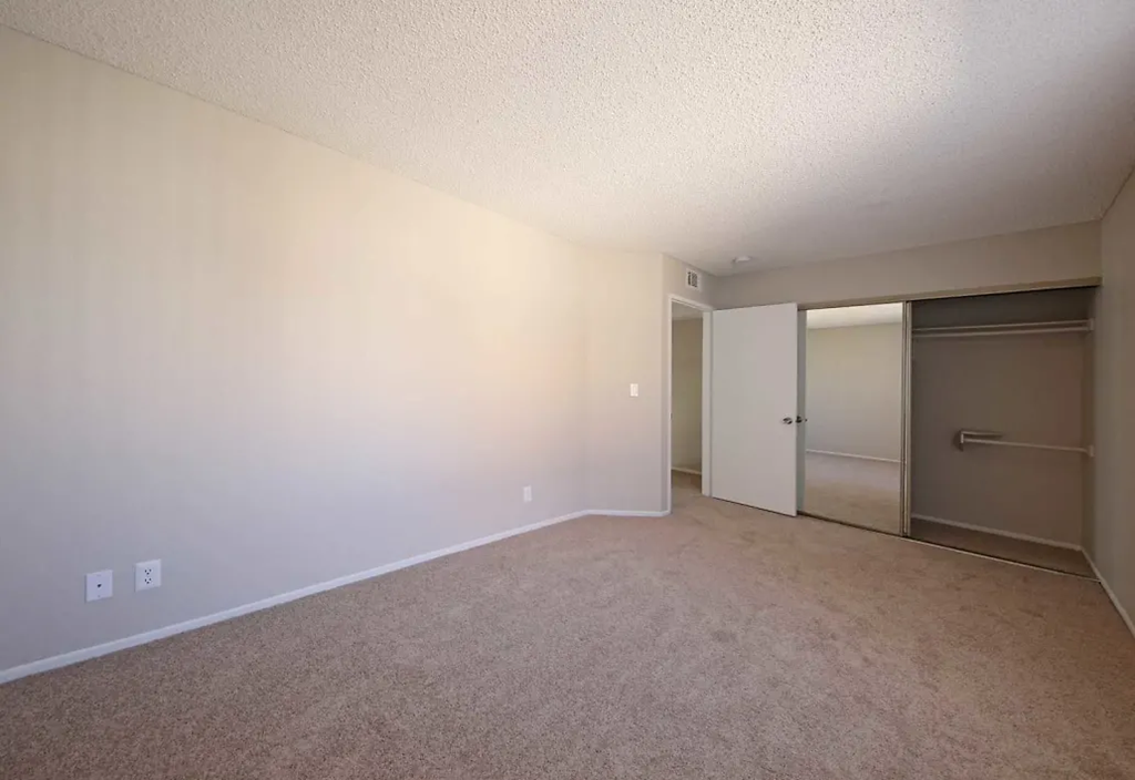 an empty living room with a door to a closet