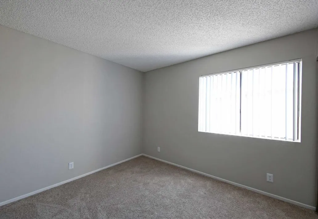 a bedroom with a large window and carpeted floor