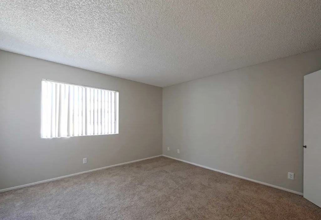 an empty living room with a window and carpet
