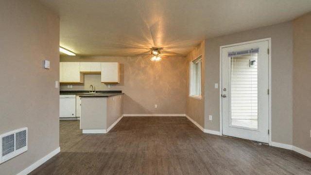 an empty room with a kitchen and a door