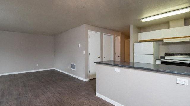 an empty living room and kitchen with a stove and refrigerator