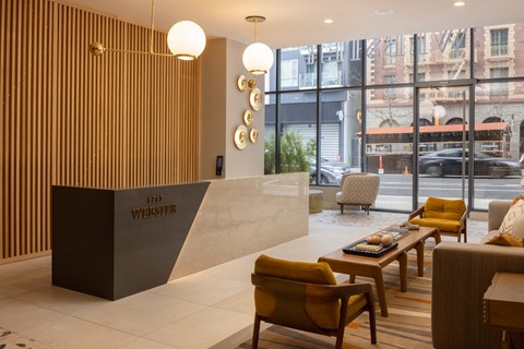 the lobby of a hotel with yellow chairs and a reception desk