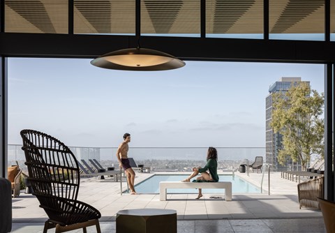 a man and a woman sitting on a bench next to a swimming pool