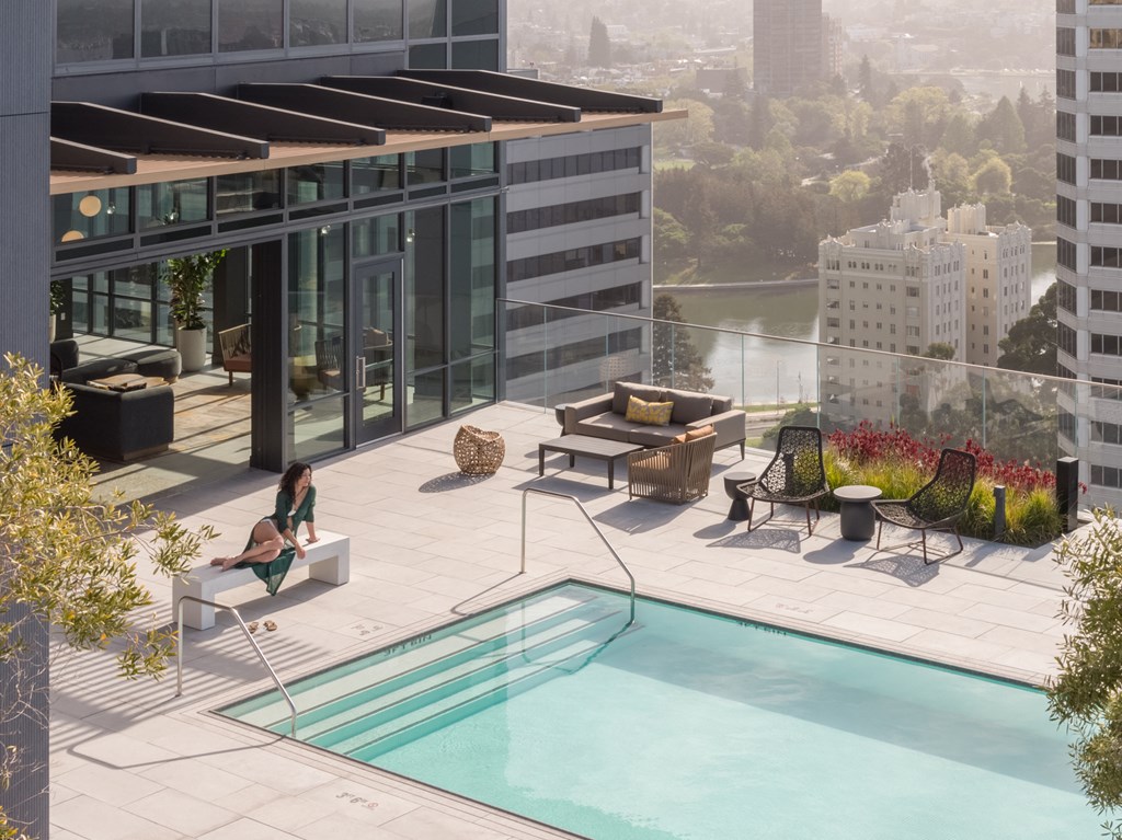 a woman sitting on a bench next to a swimming pool on top of a building