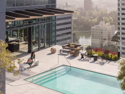 a woman sitting on a bench next to a swimming pool on top of a building