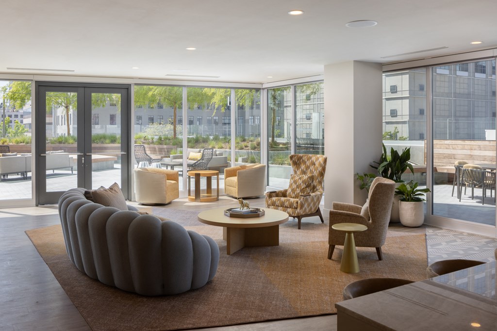 a living room with a couch and chairs in a building with glass doors