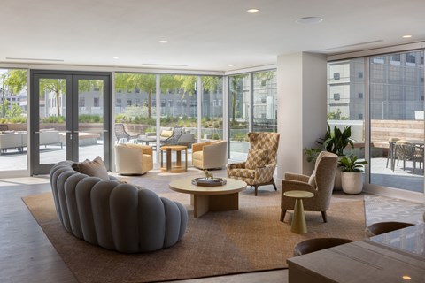 a living room with a couch and chairs in a building with glass doors