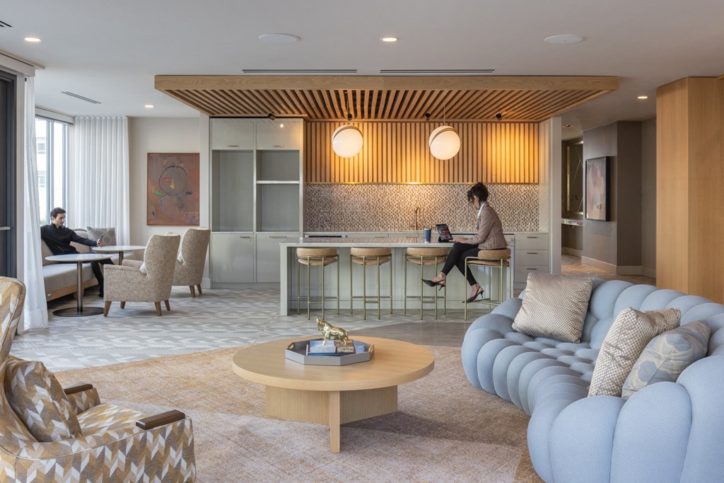 a woman sits on a couch in a living room with a bar and a kitchen