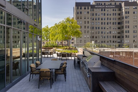 a patio with tables and chairs and a grill on a roof