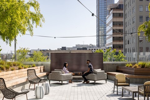 a man and a woman sitting on chairs around a fire pit