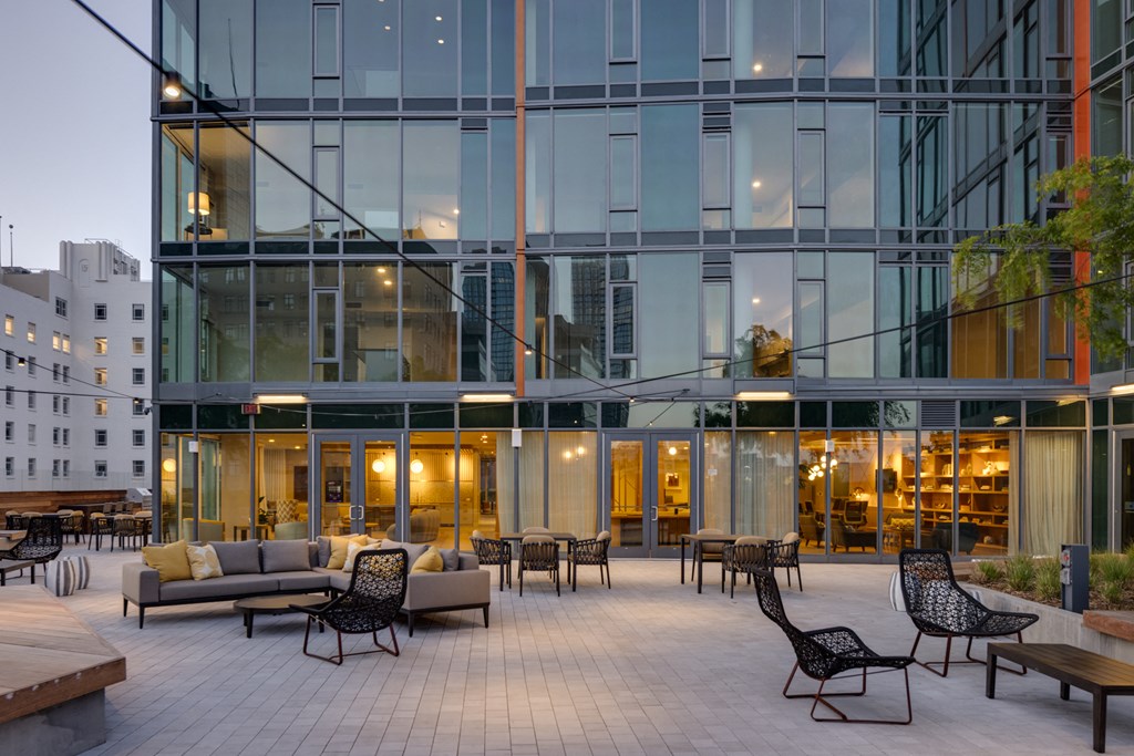 the patio of a glass facadeed building with furniture and tables