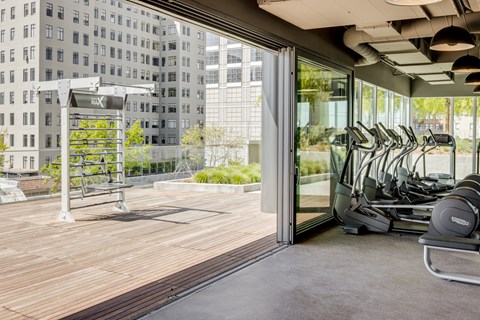 the gym on the roof of the building has cardio equipment and a large window