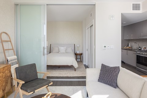 a bedroom with a bed and a living room with a couch and a chair