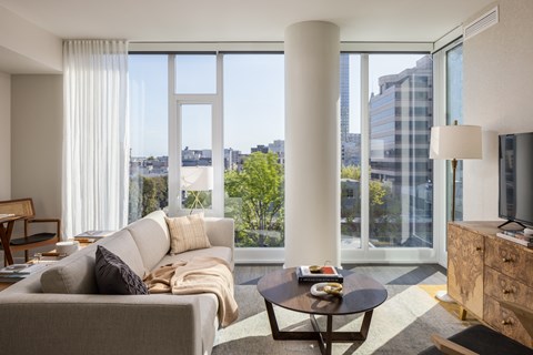 a living room with a couch and a coffee table and large windows